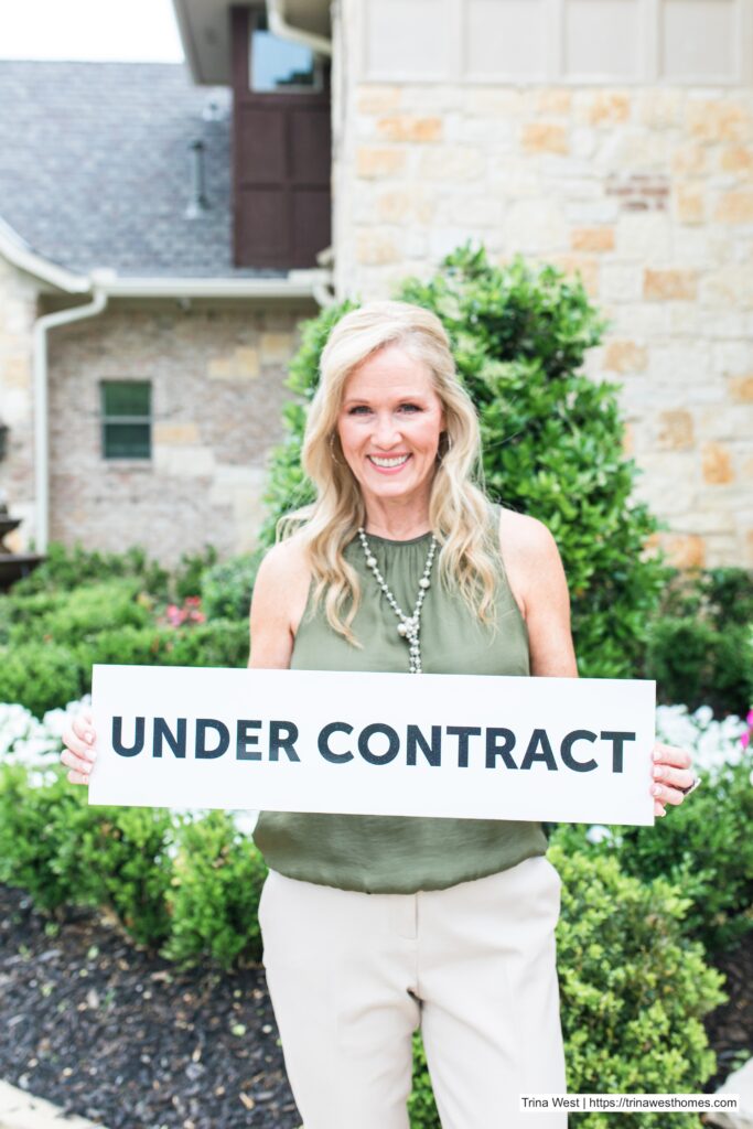 Trina West is holding an Under Contract sign in front of a recently sold home
